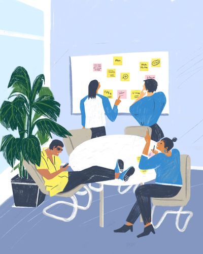 Vier Personen sitzen und stehen um ein Whiteboard herum. Eine hat die Füße auf dem Tisch, zwei kleben Post-its an.